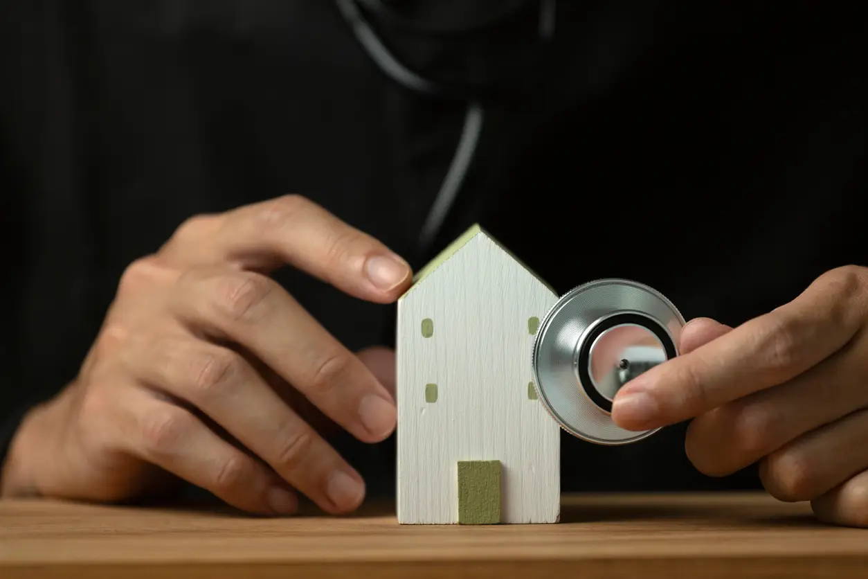 Doctor holding a stethoscope beside a model house while reviewing home loan options