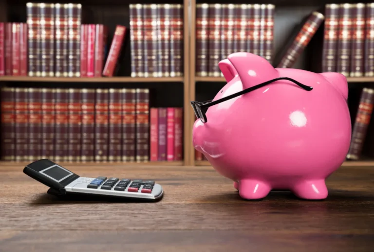 Savings loan calculator with pink piggy bank and calculator on desk