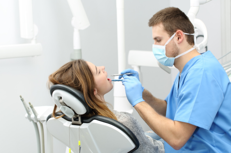 Male dentist performing a dental check-up on a female patient in a modern clinic.