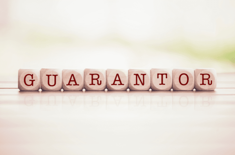 Wooden letter blocks spelling the word "GUARANTOR" on a light surface, symbolising financial support through a guarantor arrangement.