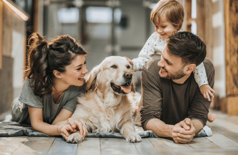 Happy young family with their dog relaxing on the floor of their new home.