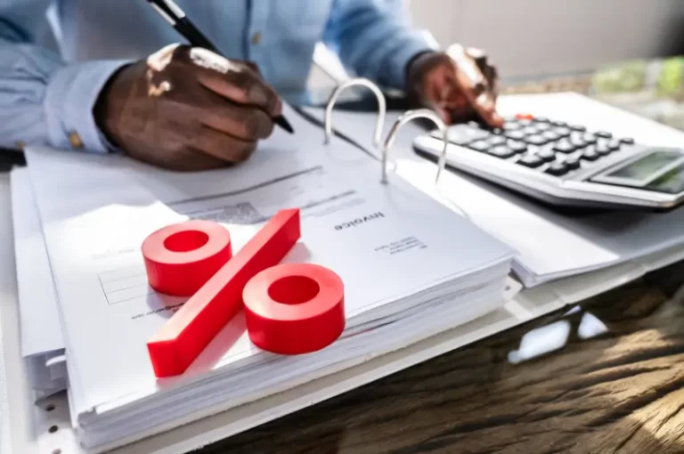 Person using a calculator with a red percentage symbol on financial documents, representing home loan interest calculations.