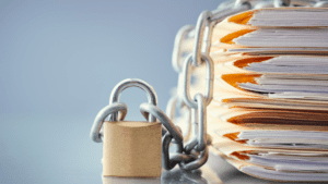 Stack of paperwork bound by a metal chain and padlock symbolising secure documentation.