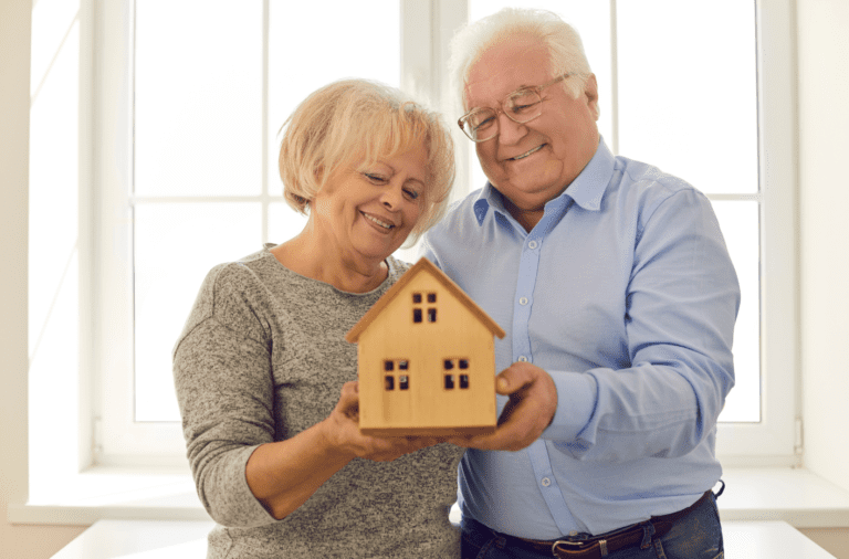 Elderly Couple with wooden house in their hands.
