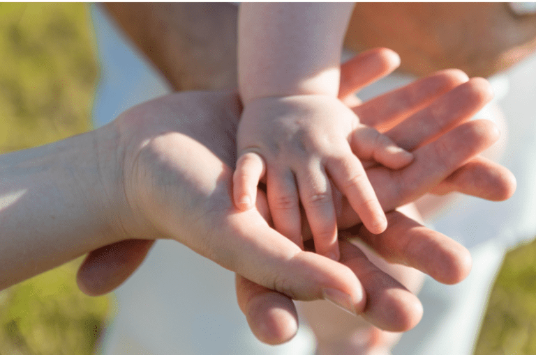 Close-up of a parent and child placing hands together in a loving gesture.