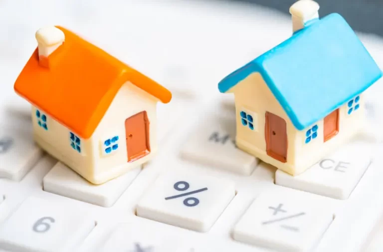 Two model houses sitting on calculator with percentage symbol.