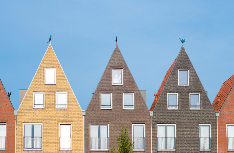 Row of nearly identical townhouses under blue sky