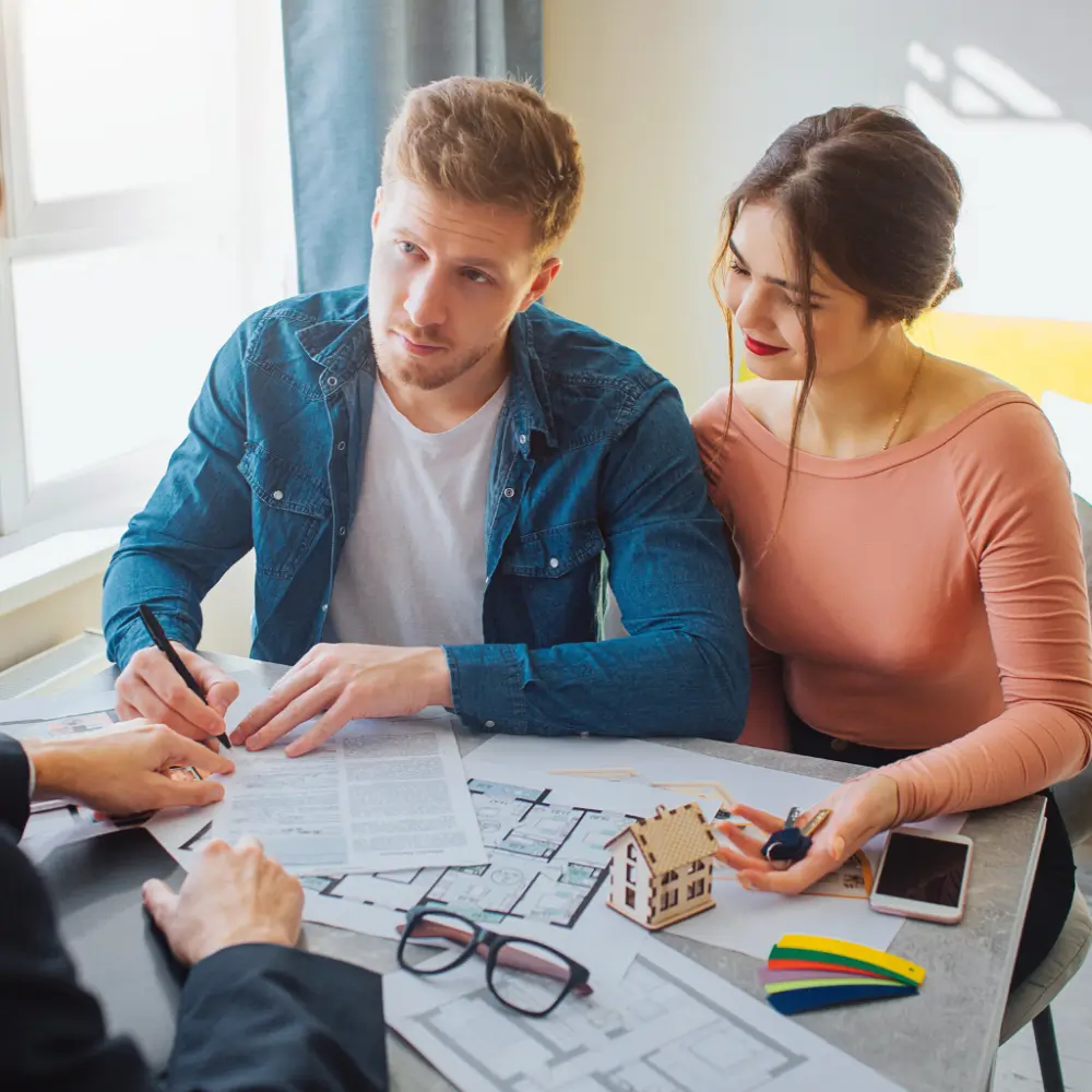 Young couple discussing home loan options with a mortgage broker in a modern office setting.