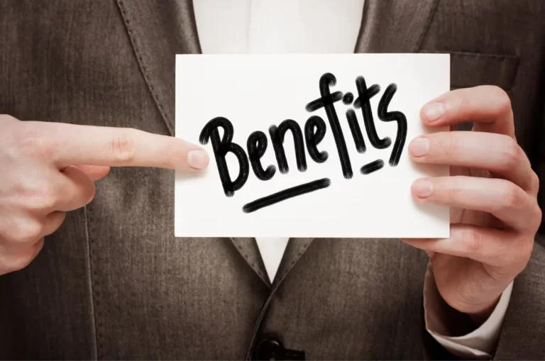 Close-up of a person in a suit holding a card with the word "Benefits" written on it