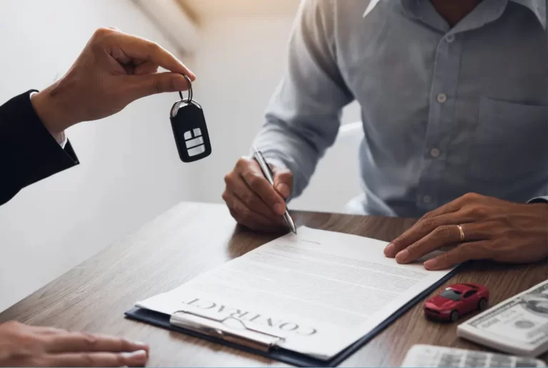 Man signing car loan contract at desk