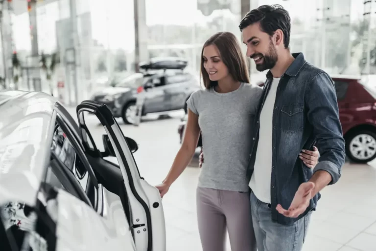 Smiling couple inspecting car at dealership