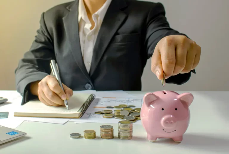 Businessman saving coins in piggy bank