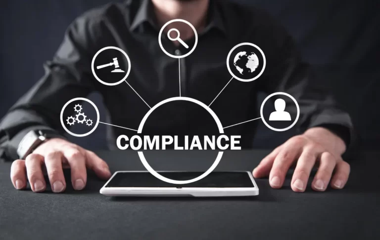 Businessperson at a desk with a tablet, surrounded by compliance-related icons and the word 'COMPLIANCE' highlighted.