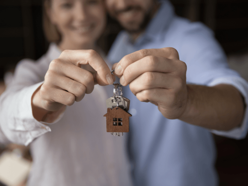 Happy first home buyers holding house keys symbolising their first property purchase